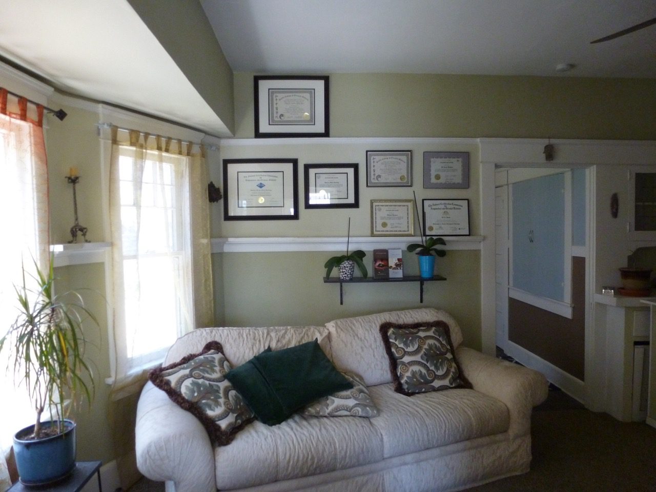 A living room with a couch and several framed pictures on the wall.