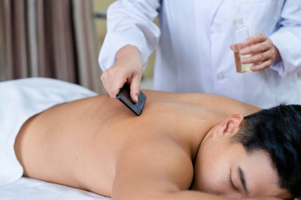A man getting his back shaved by a masseur.